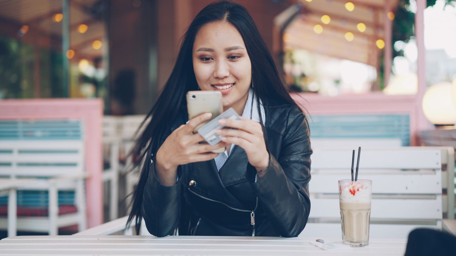 A smiling woman looking at her phone at a café table